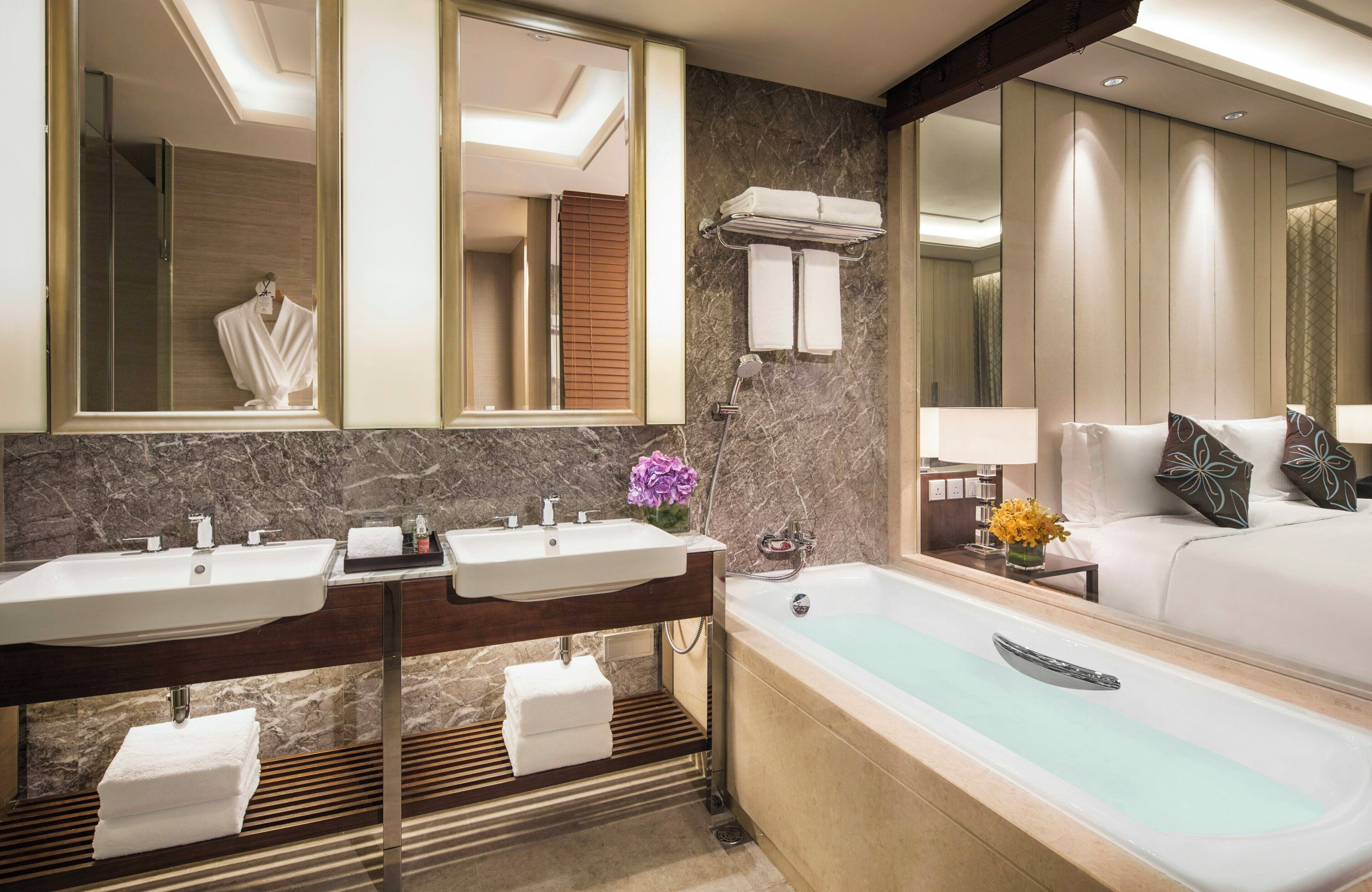 A modern bathroom with two sinks, a bathtub, and a large mirror.