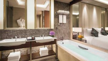 A modern bathroom with two sinks, a bathtub, and a large mirror.