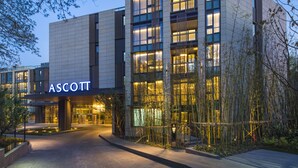 Um edifício moderno com o nome "ASCOTT" em destaque na fachada.