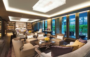 A modern lounge area with sofas, armchairs, and a coffee table, featuring large windows and a bookshelf. - Ascott Heng Shan Shanghai (Shanghai)