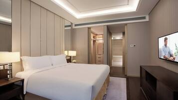 A hotel room with a large bed, bedside lamps, a TV, and a walk-in closet.