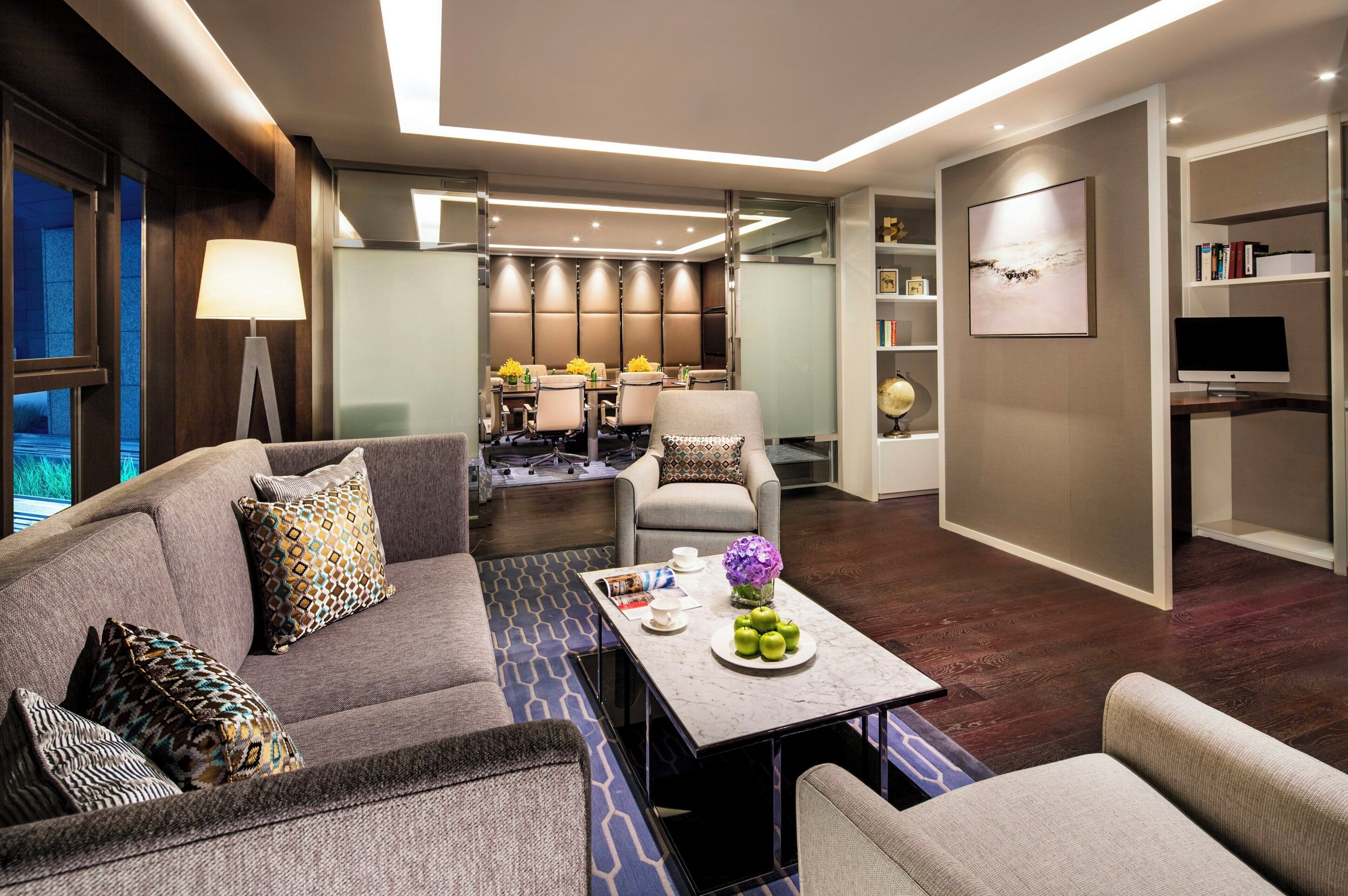 A modern living room with a sofa, armchairs, a coffee table, and a dining area with a table and chairs.