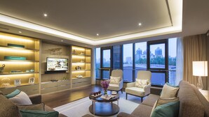 Una sala de estar moderna con televisor de pantalla plana, asientos cómodos y vista a la ciudad.