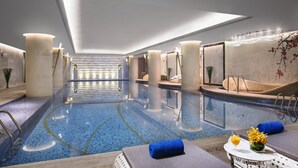 Uma área de piscina interior ampla, com água cristalina, vários espaços para relaxar e design moderno.