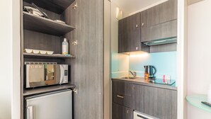 A compact kitchen with a microwave, refrigerator, and a coffee maker on the counter. - Appart'City Confort Montpellier Ovalie 2 (Montpellier)