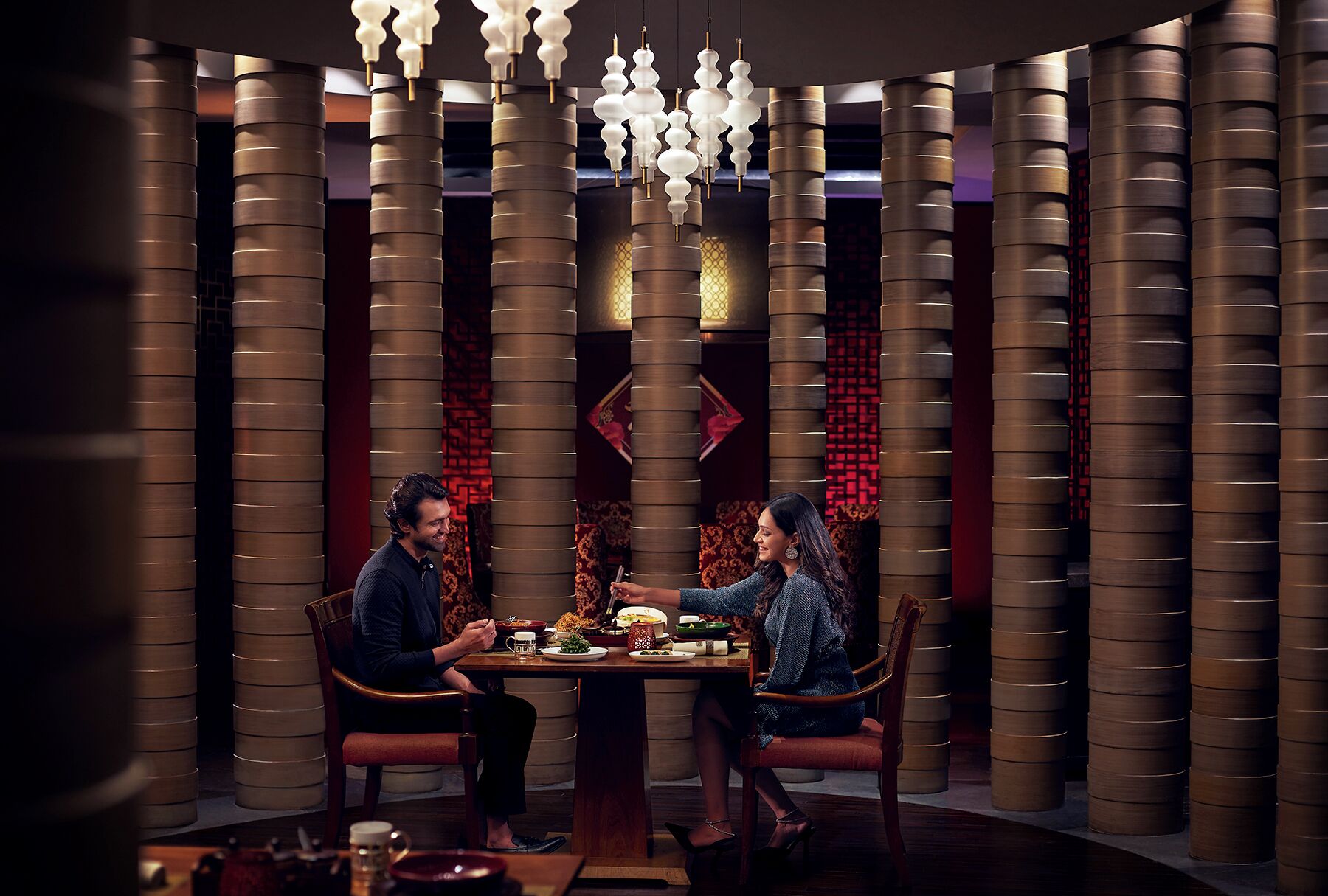 A dining area with a round table, two chairs, and a decorative ceiling light.