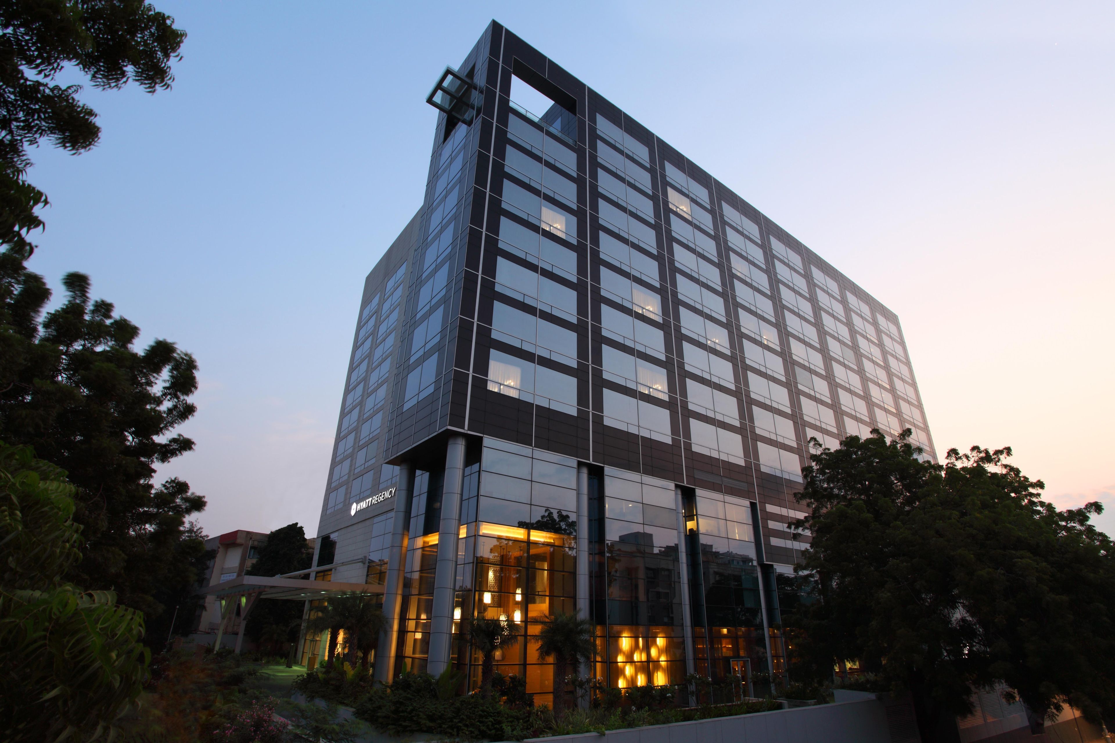 A modern hotel building with a glass facade, multiple floors, and a well-lit entrance.
