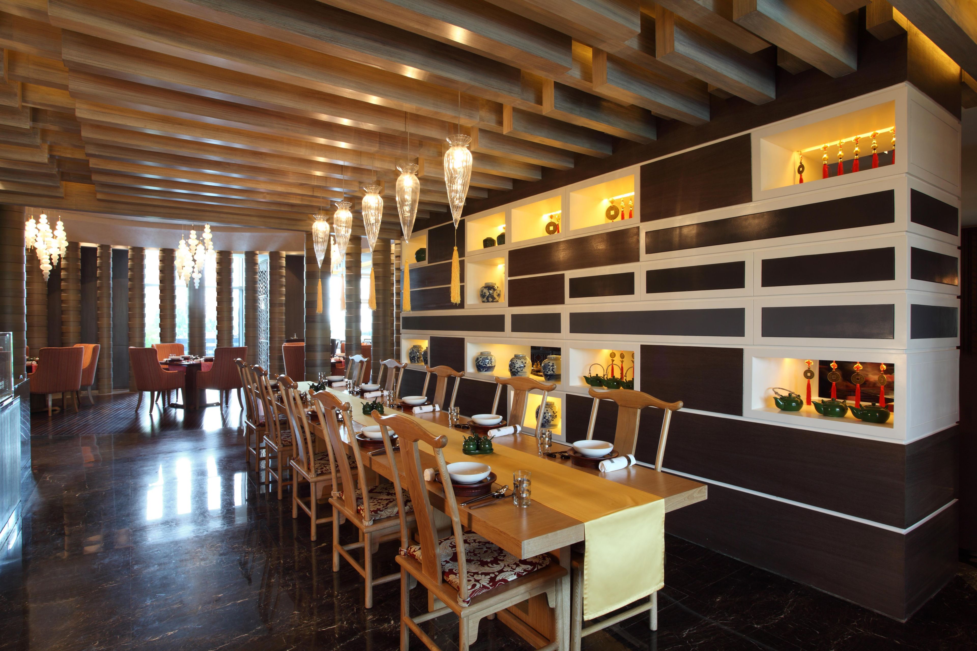 Un comedor con una larga mesa de madera, varias sillas y lámparas colgantes.