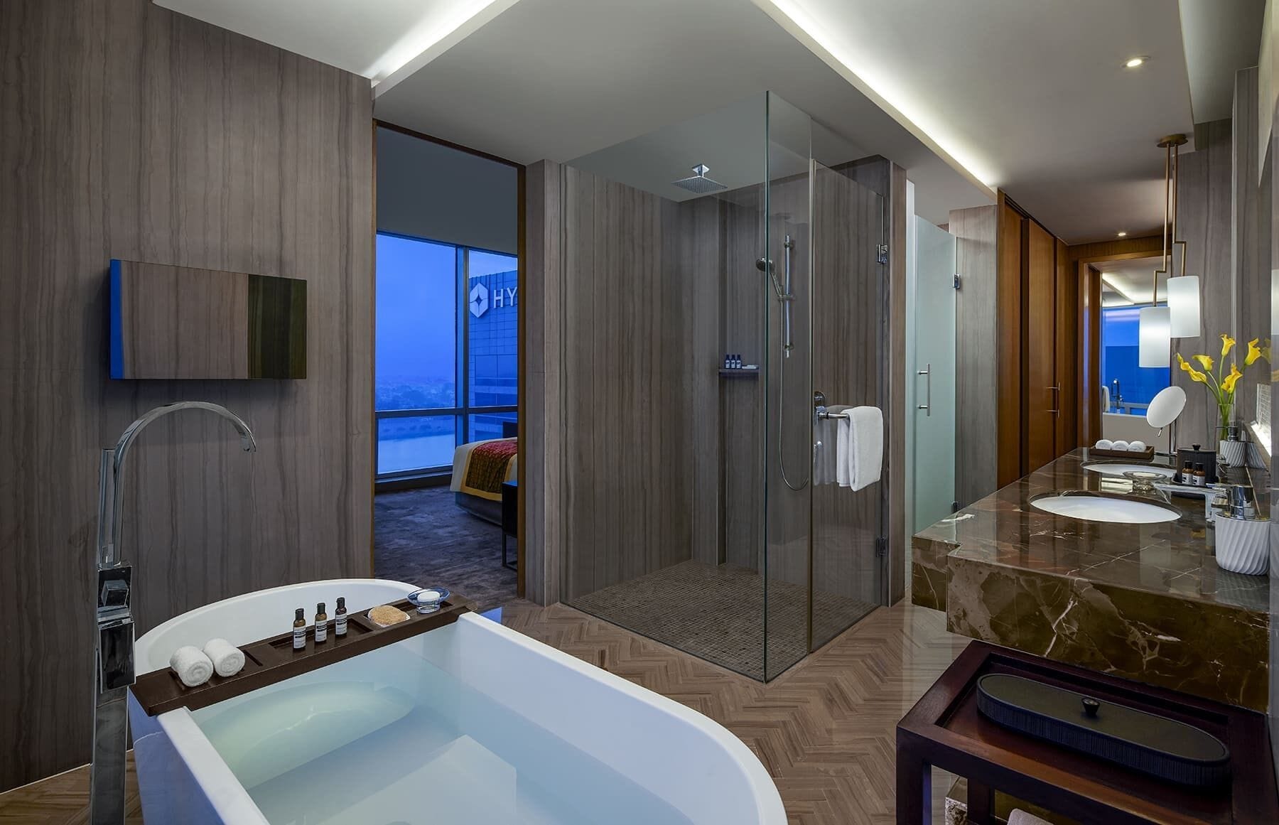 A modern bathroom with a large bathtub, a walk-in shower, and a vanity with a marble countertop.