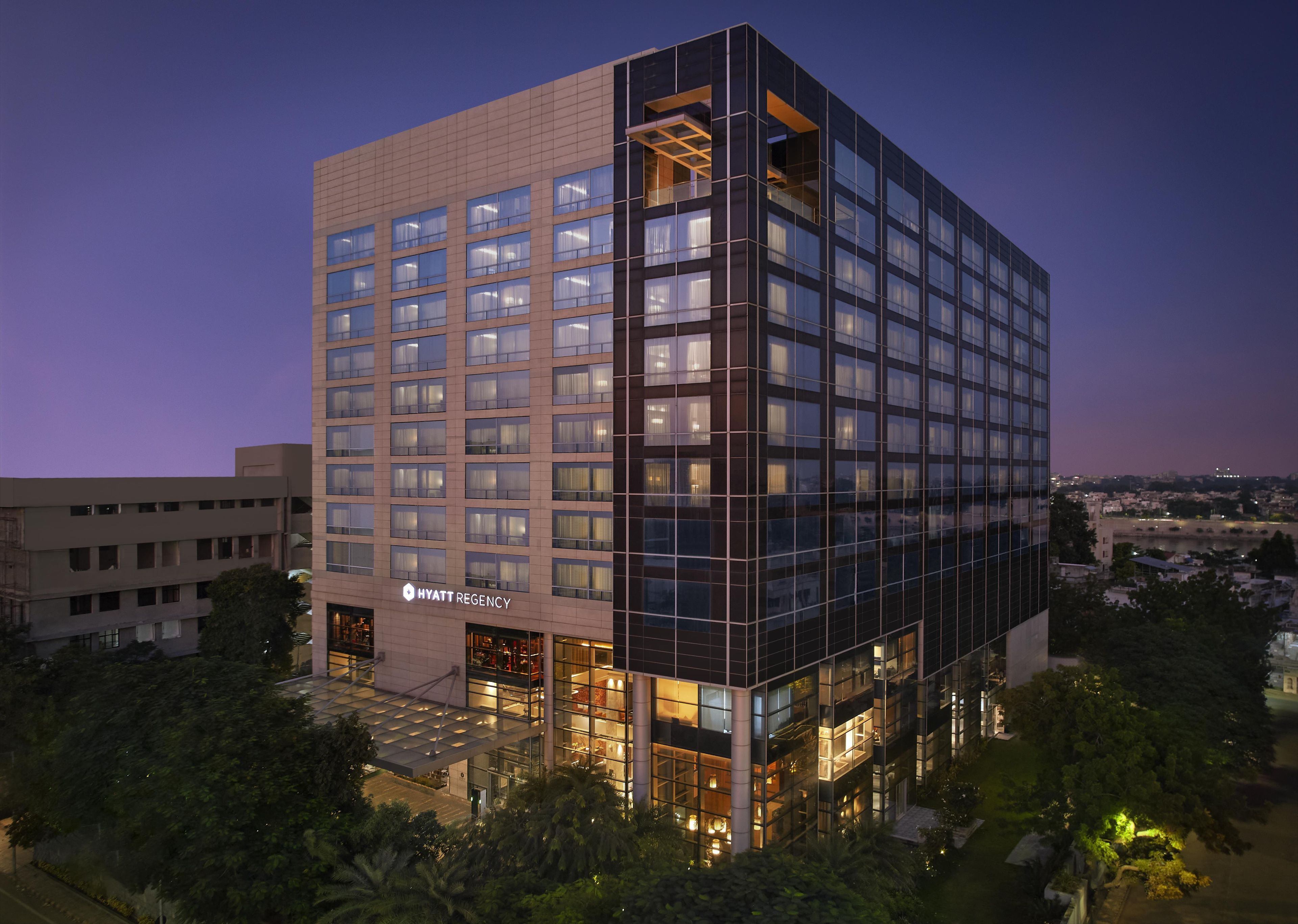 A multi-story hotel with a glass facade, a visible sign for 'HYATT REGENCY,' and a modern architectural design.