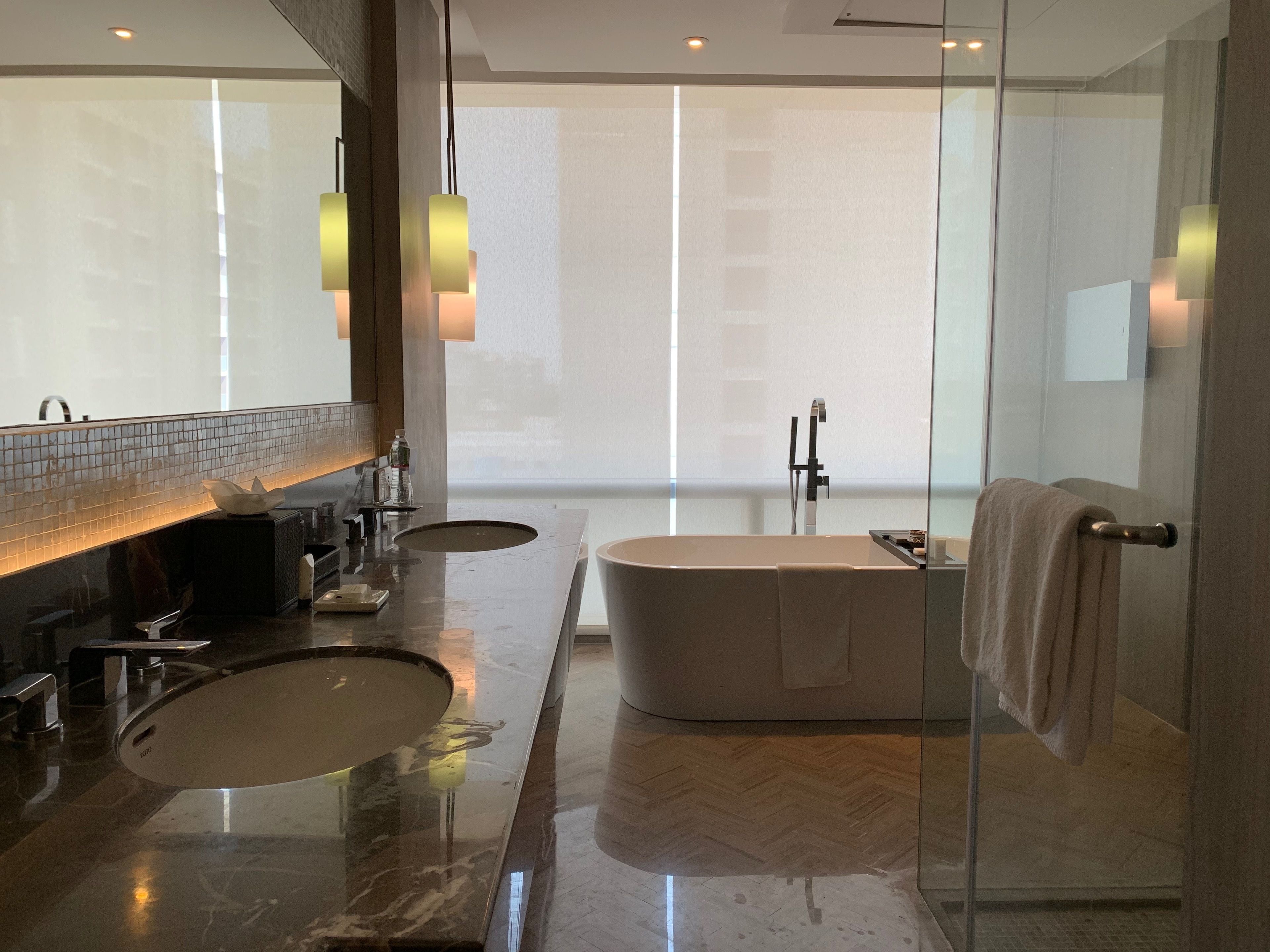 A modern bathroom with a large bathtub, a separate sink, and a glass shower enclosure.