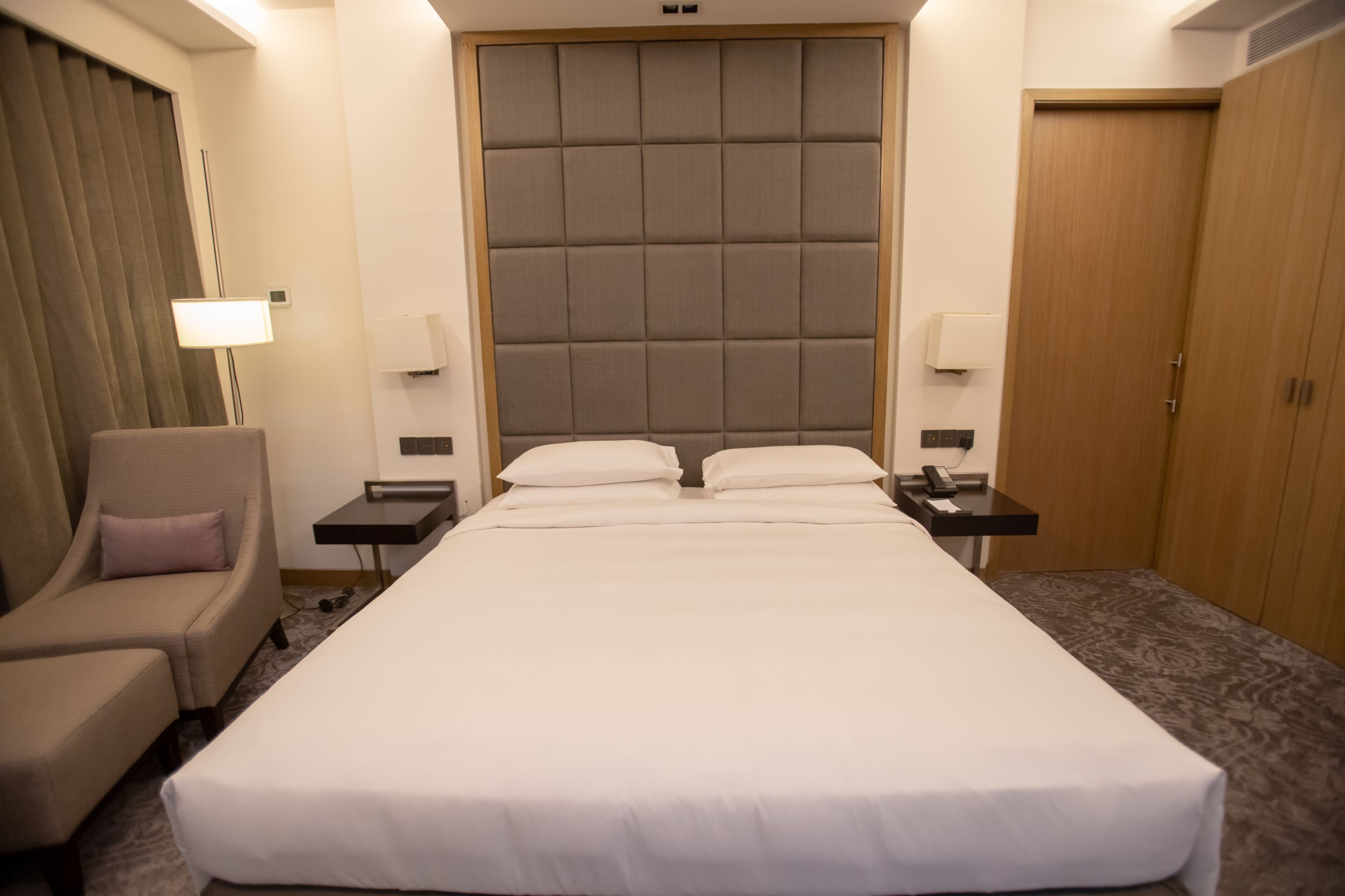 Una camera d'albergo con un letto grande, una sedia, comodini e un armadio.