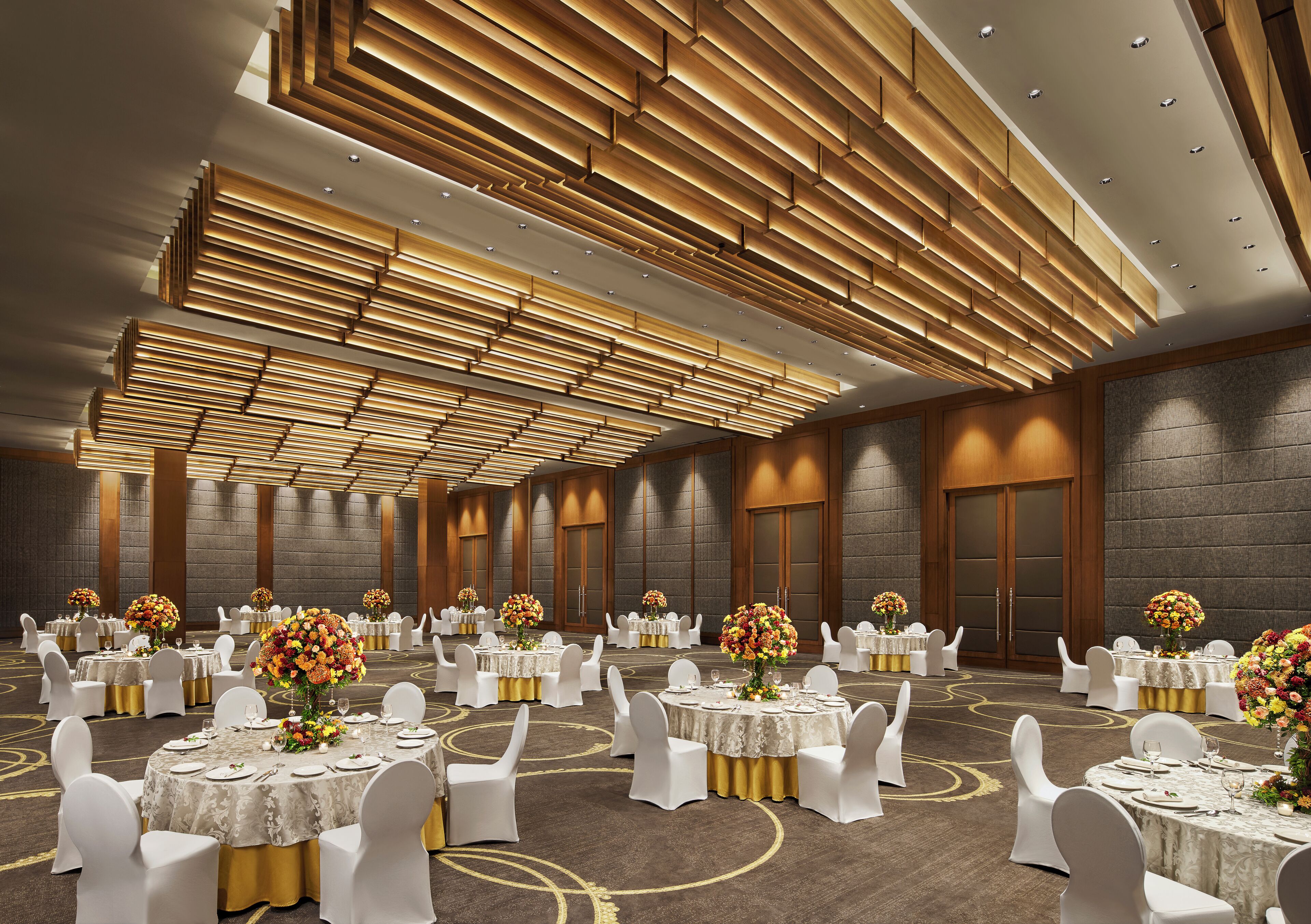 A spacious banquet hall with round tables, white chairs, and floral centerpieces.
