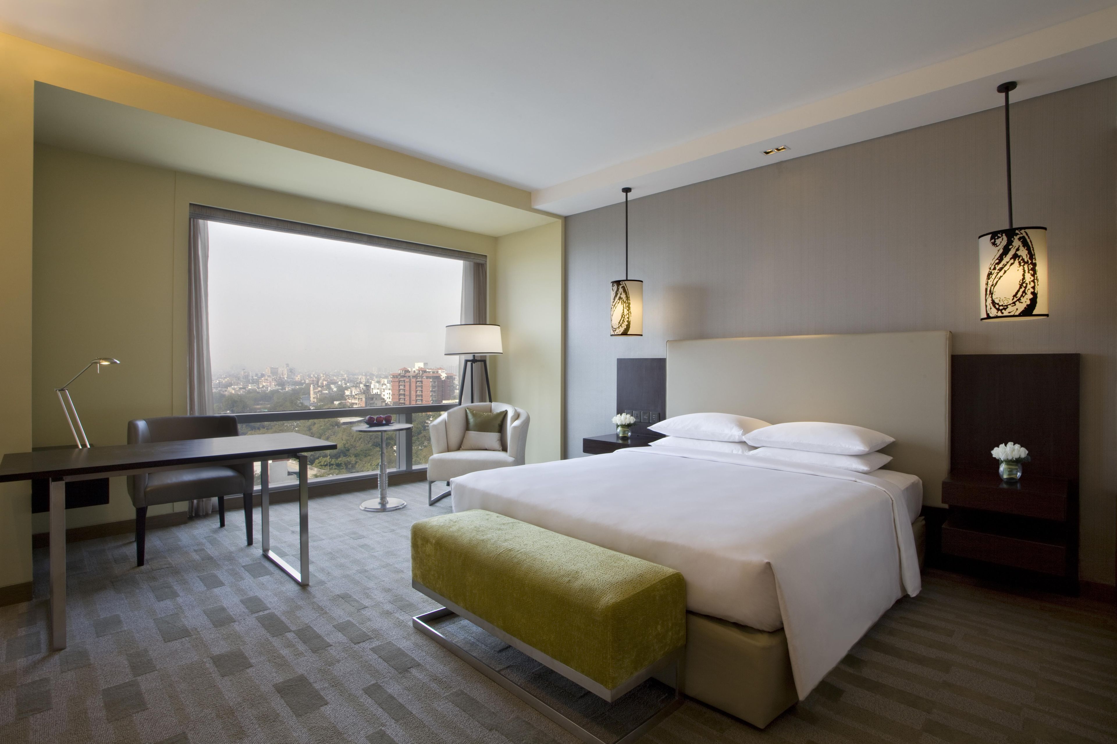 Habitación de hotel con cama, escritorio, silla y vistas a la ciudad.