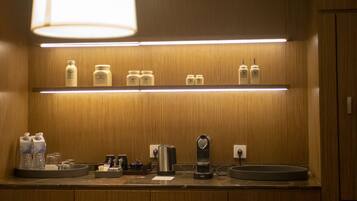 Uma cozinha compacta com armários de madeira, bancada com diversos eletrodomésticos e luminária pendente.