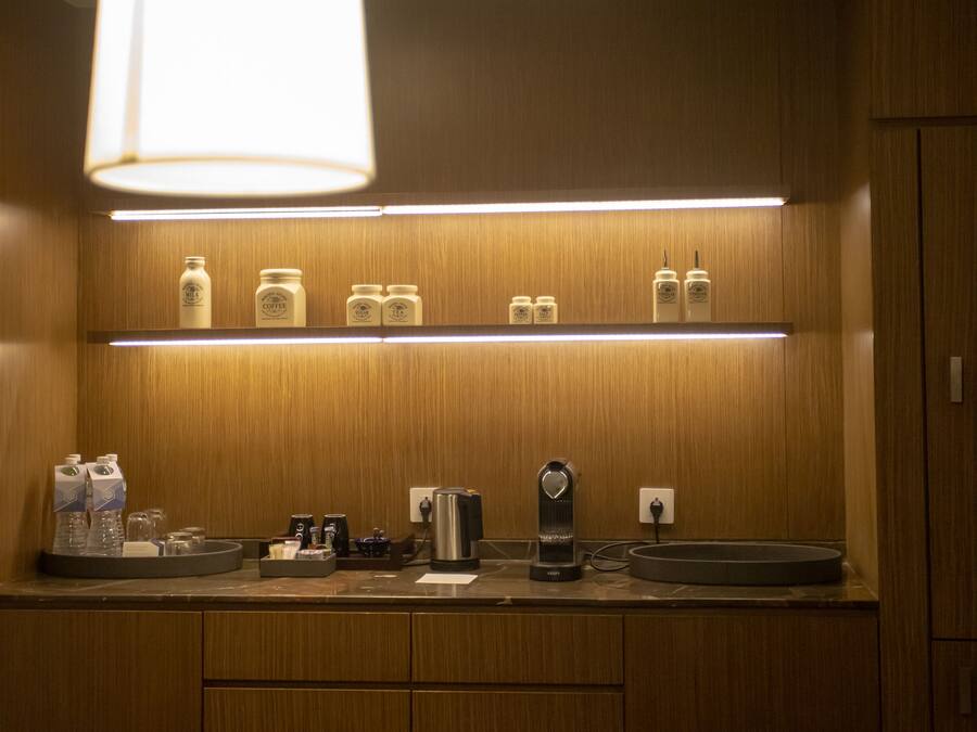Uma cozinha compacta com armários de madeira, bancada com diversos eletrodomésticos e luminária pendente.