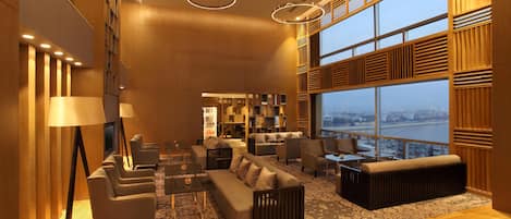 A modern interior with a sofa set, armchairs, a coffee table, and a large window offering a city view.