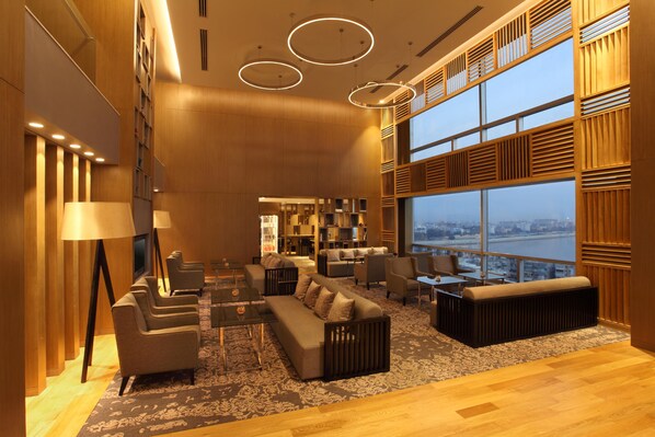 Un interior moderno con un conjunto de sofá, sillones, una mesa de centro y un ventanal con vistas a la ciudad.