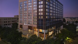 A modern hotel with a glass facade, multiple floors, and a visible sign for the Hyatt Regency.