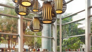 A dining area with a glass wall, a three-tiered tea service table, and multiple hanging lamps.