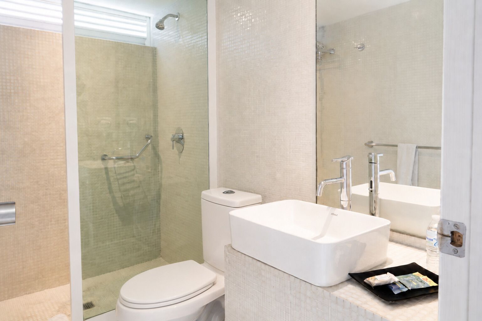 A modern bathroom with a glass-enclosed shower, a white toilet, and a large rectangular sink with a mirror above it.