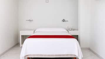 Habitación de hotel con cama, dos mesitas de noche y un detalle rojo en la colcha.