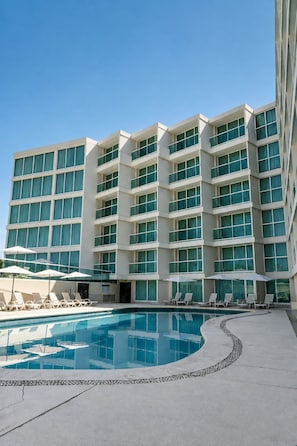 A modern hotel with a large pool area, multiple balconies, and sun loungers. - We Hotel Acapulco (Acapulco)