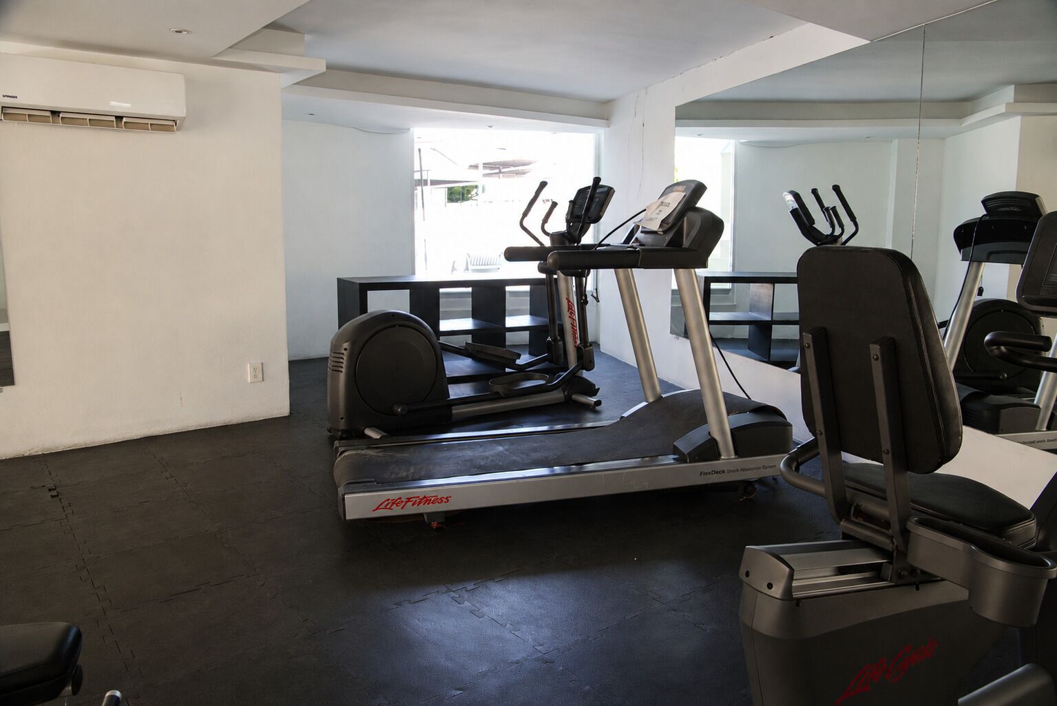 A gym with a treadmill, elliptical, and stationary bikes.