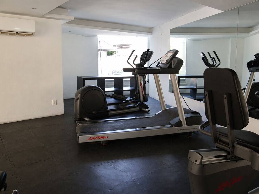 Une salle de sport équipée de tapis de course, de vélos elliptiques et de vélos d’appartement.