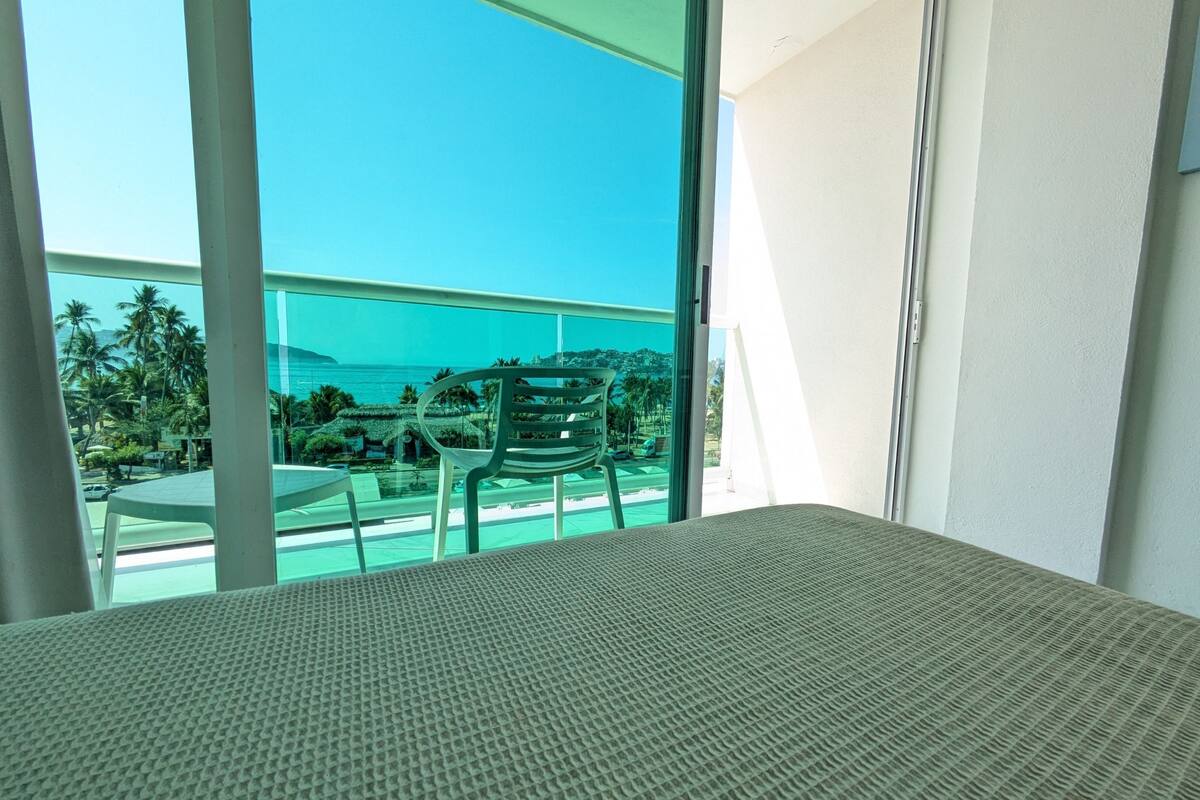 A room with a view of a pool and palm trees.