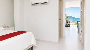 Une chambre d’hôtel équipée d’un lit, d’un téléphone, de la climatisation et offrant une vue sur la mer depuis un balcon.