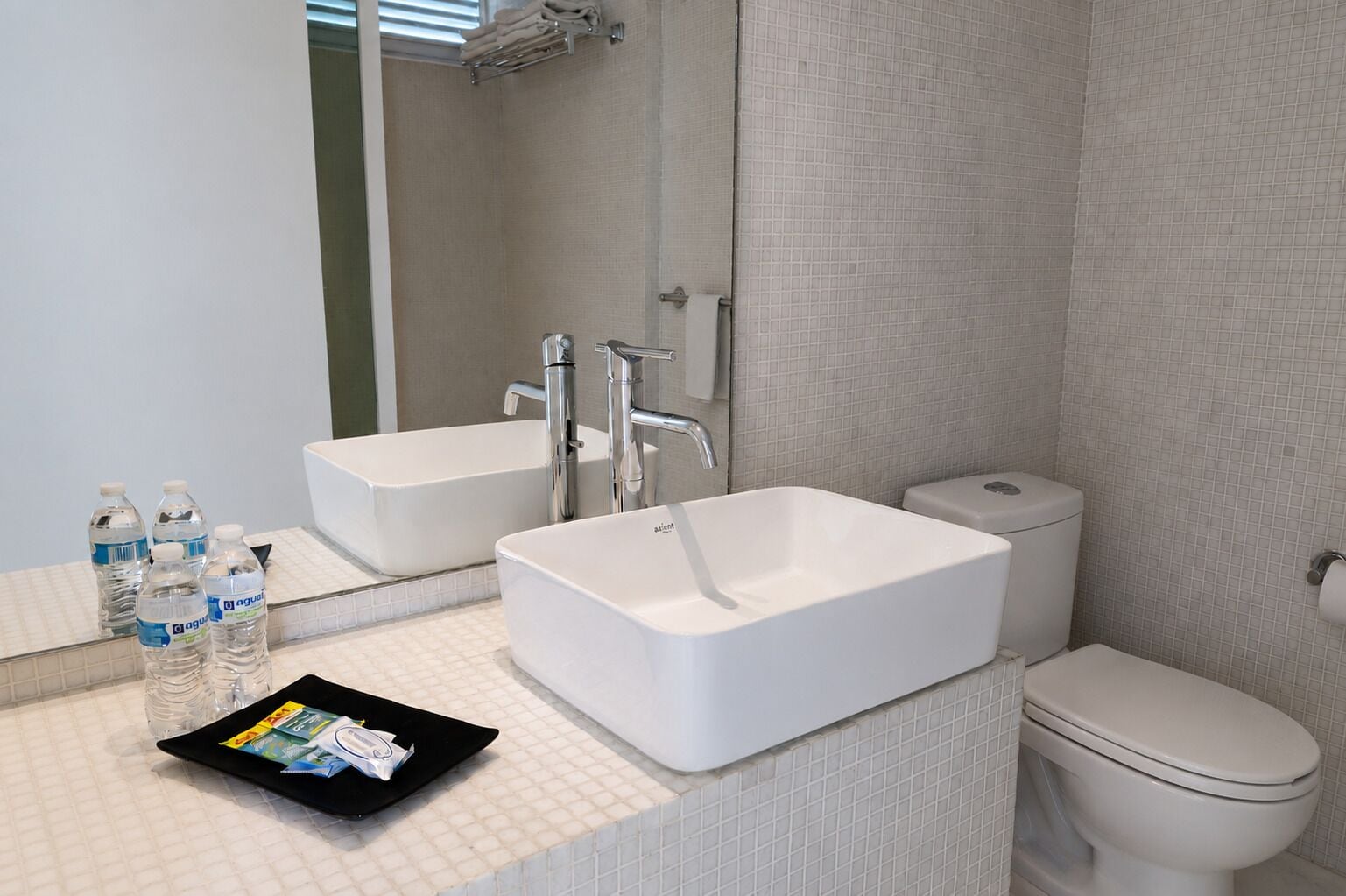 Un baño con lavamanos blanco, un espejo, un inodoro y un perchero para toallas.