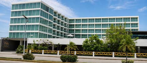 A modern hotel with a multi-story structure, large windows, and a gated entrance.