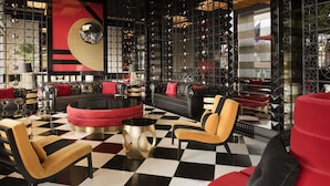 Un salón moderno con piso a cuadros, asientos en rojo y negro, y espejos decorativos.