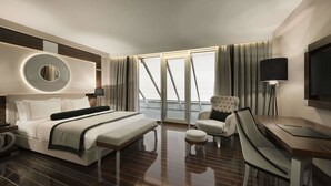 Habitación de hotel moderna con una cama grande, un escritorio con silla, un espejo redondo y una televisión.