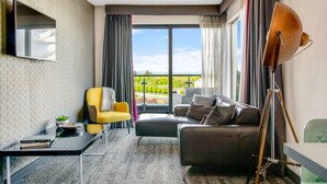 A modern living room with a large window, a flat-screen TV, a yellow armchair, a leather sofa, and a floor lamp. - Roomzzz Chester City (Chester)