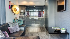 A modern living room with a sofa, a coffee table, and a TV mounted on the wall. - Roomzzz Chester City (Chester)