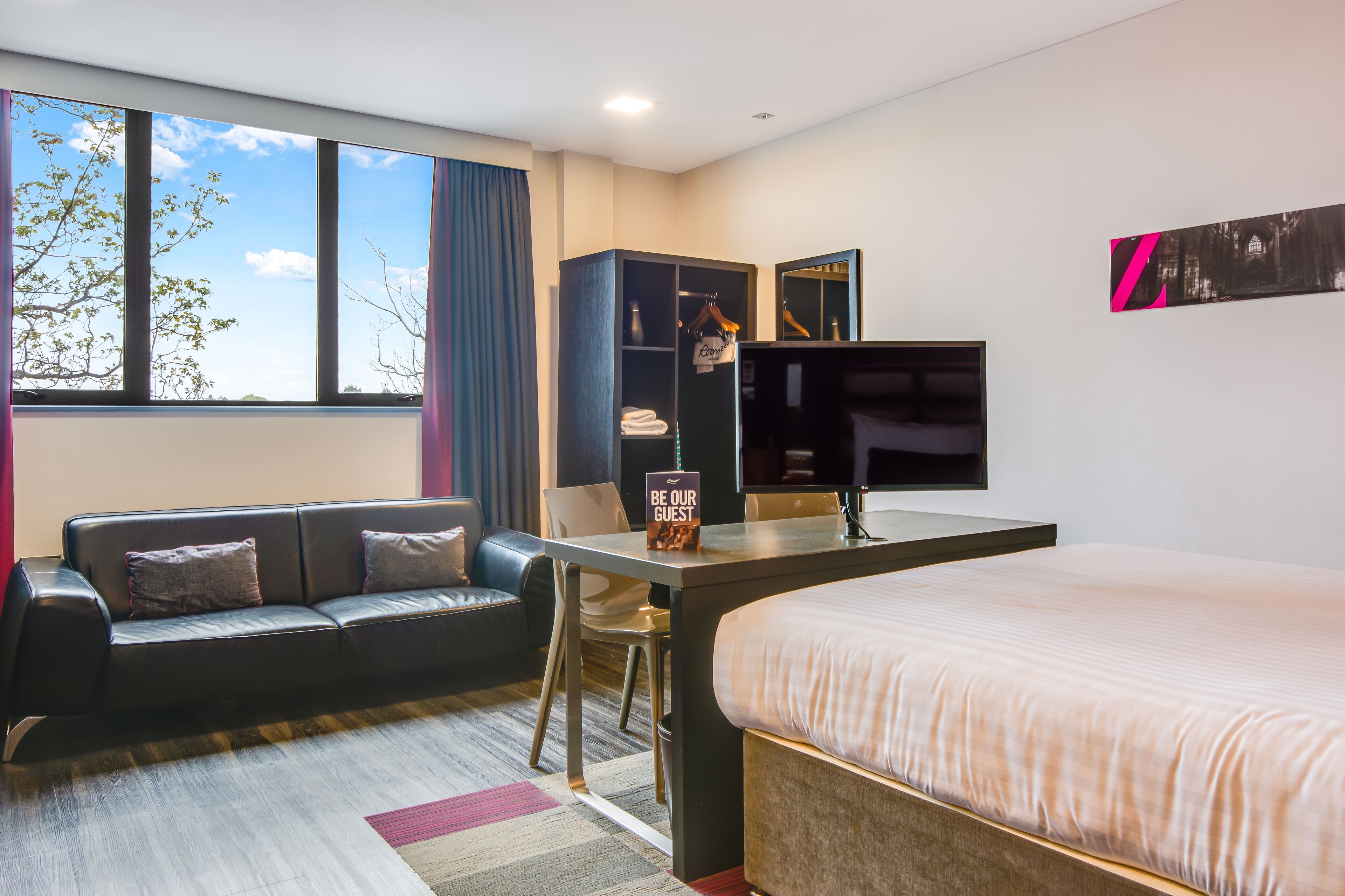 Una habitación de hotel con cama, escritorio, sofá y armario.