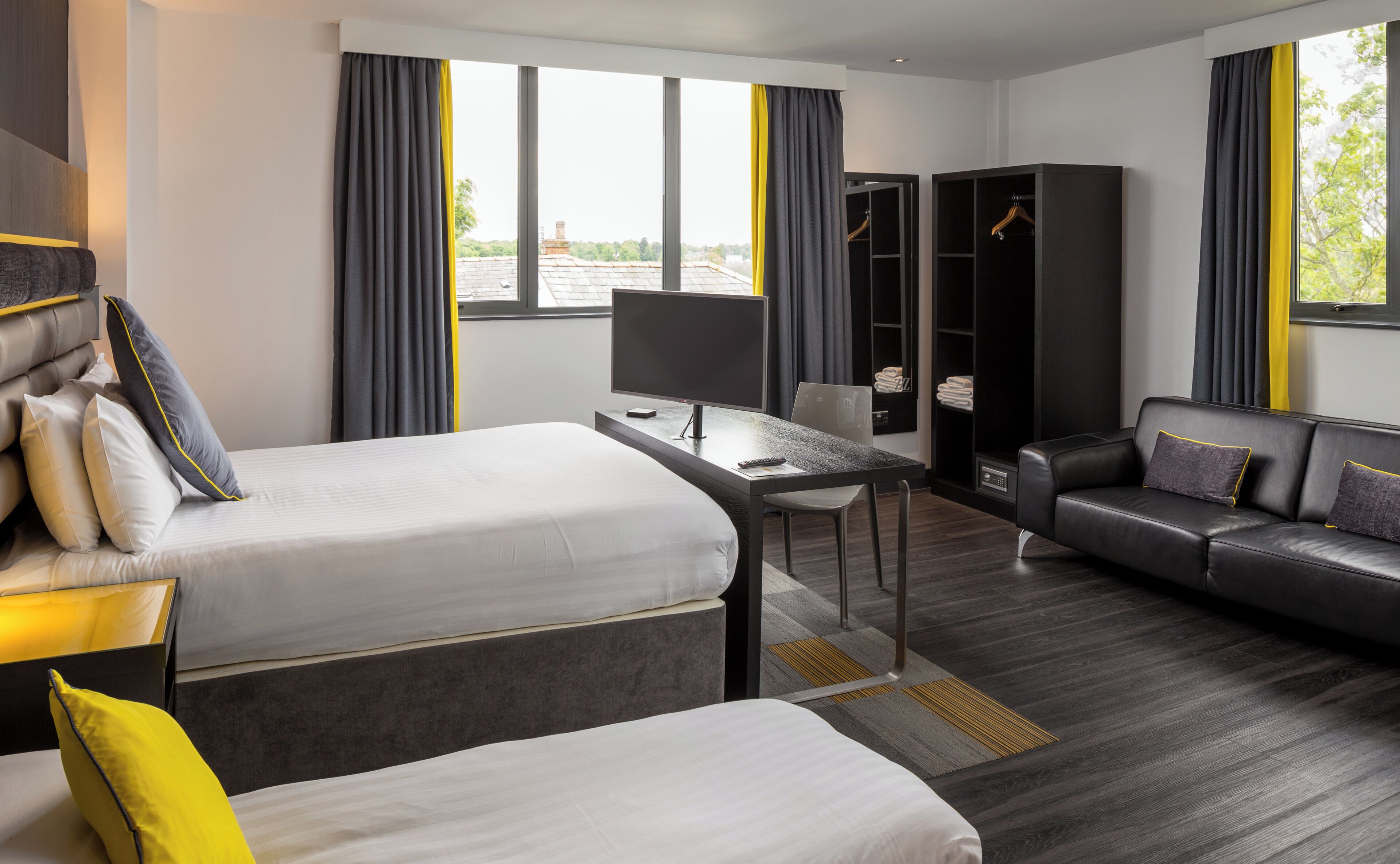 Une chambre d’hôtel moderne équipée d’un lit, d’un bureau, d’un canapé et d’une armoire.