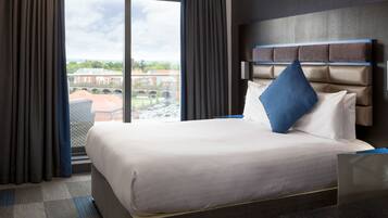 A hotel room with a large bed, a view of a cityscape through a window, and a modern headboard.