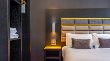 Une chambre d’hôtel avec un grand lit, une table de chevet avec une lampe et une armoire.