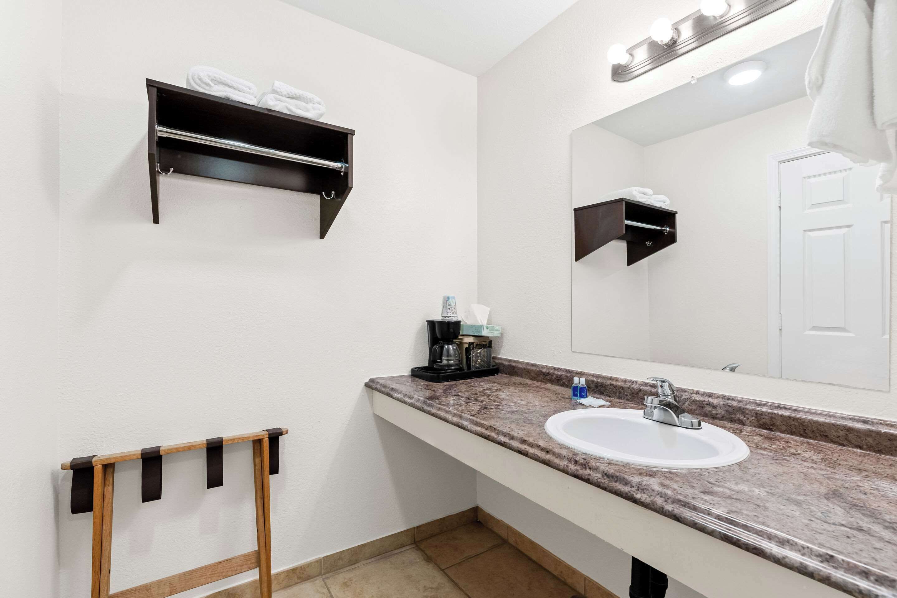 Une salle de bain avec un lavabo blanc, un miroir, un porte-serviettes et une étagère avec des serviettes.
