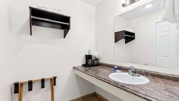 Une salle de bain avec un lavabo blanc, un miroir, un porte-serviettes et une étagère avec des serviettes.