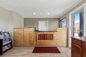 A reception area with wooden paneling, a red rug, and a display of magazines.