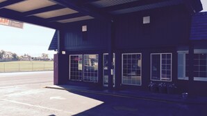 En bygning med overdækket indgang, store vinduer og parkeringsplads.