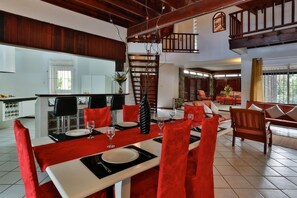 A dining area with a high ceiling, a staircase, and a view of the kitchen. - Villa Harmony (Gros Islet)