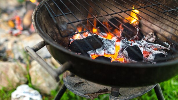En närbild på en grill med glödande kol och lågor.