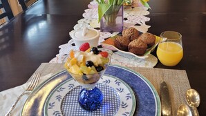 A dining table with a fruit salad, muffins, and orange juice. - OKeefe's Landing Bed & Breakfast (Vernon)