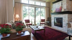 A living room with a fireplace, a sofa, a coffee table, and a dining area. - OKeefe's Landing Bed & Breakfast (Vernon)