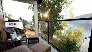 A balcony with wicker furniture and a view of a lake. - OKeefe's Landing Bed & Breakfast (Vernon)